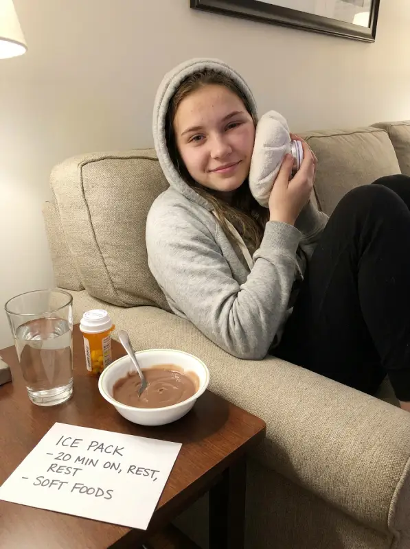 Teenage patient resting at home with an ice pack after wisdom teeth removal in Murrieta